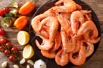 Dish with large shrimp and fresh vegetables close-up on a table. Horizontal top view from above