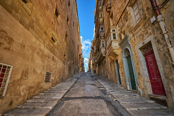Narrow street in Valletta city going upward between big houses