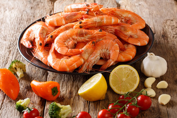 Dish with large shrimp and fresh vegetables close-up on a wooden table. horizontal