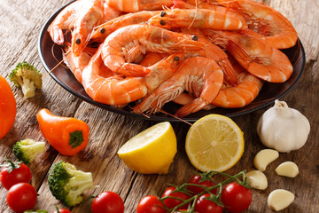 boiled tiger shrimps on a plate and fresh vegetables close-up on a table. horizontal