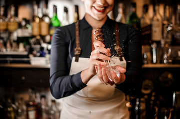Smiling barman girl crushing a piece of ice for making a cocktail