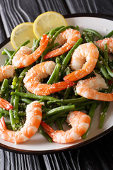 seafood shrimp salad with green beans, cheese and lemon close-up on a plate. vertical