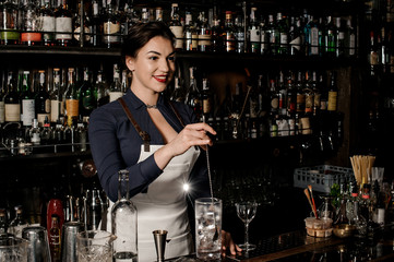 Beautiful smiling barman woman stirring fresh summer drink