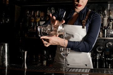 Beautiful barman woman pouring fresh cocktail into a glass