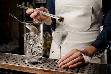 Bartender hand putting an olive into a cocktail glass