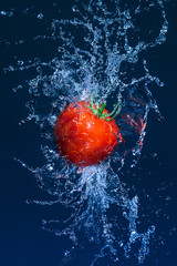 Flying ripe tomato in water splashes