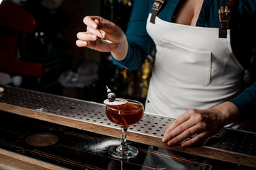Barmaid decorating a strong sweet summer cocktail with sugar powder