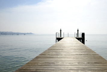 Wooden pier over lake against sky. Bardolino, Italy