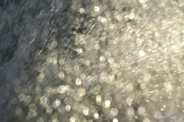 Splashing water shining in the blurry light. Blurred splashes of water drops in the setting sun.