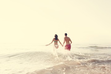 Happy couple running into the water