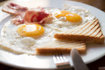  fried eggs with bacon and toasts on a white plate