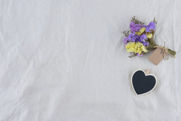 Tiny heart blackboard with statice flowers bouquet with card on white muslin fabric with copy space