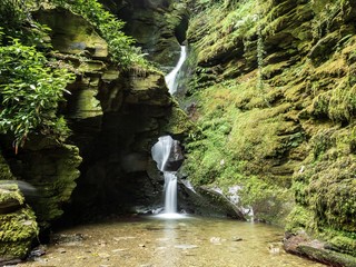 A waterfall through a hole in the rock at St Nectan's Glen in Cornwall