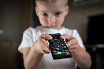 child with a TV remote control in hands