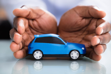 Businessman's Hand Protecting Blue Toy Car