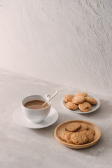 Cup of coffee with milk or cappuccino with cookies on light stone background. Drink with caffeine or cocoa with milk. Coffee break concept.