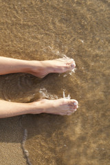 Female legs on sand washed with sea