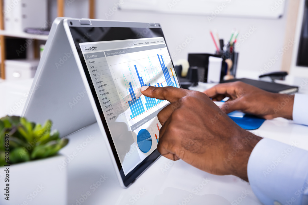 Aufkleber man's hand pointing on graph at laptop