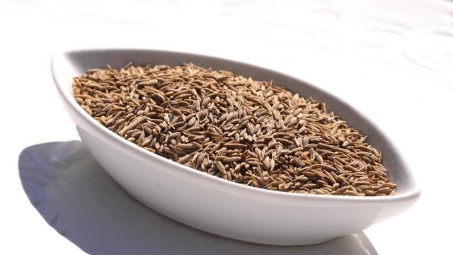 Dry spices cumin seeds on a rotary table. 4K. Macroshooting.