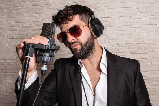  Singer with sunglasses in front of a microphone holding him by hand and with some helmets