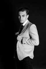 Close-up portrait of a good looking beautiful young man in costume on black background. Black-white photo.
