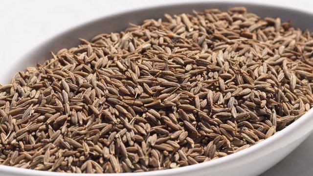 Dry spices cumin seeds on a rotary table. 4K. Macroshooting.