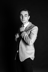 Close-up portrait of a good looking beautiful young man in costume on black background. Black-white photo.