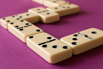 Playing dominoes on a purple background . The concept of the game of dominoes. Close up