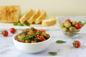 Caponata or ratatouille from a variety of vegetables served with ciabatta and olive.