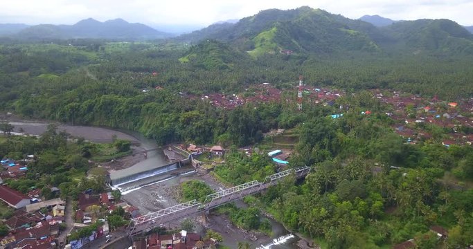 Aerial: Metallic bridge over river near Tirai Air Terjun and falls of Dam Tukad Yeh Unda Klungkung ,the city of Semarapura,Bali island,Indonesia