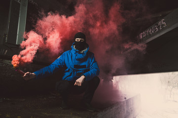 A football fan with a smoke bomb in his hands. Ultras fan with pyrotechnics in hand. A football fan...
