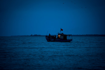 Naklejka premium Fishing boat goes to sea. Ship at sea. Seiner goes to sea. A ship at dawn in the sea. Fishing boat at night at sea.