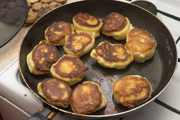 Pancakes or dumplings are fried in a frying pan on vegetable oil, close-up