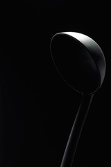 Black ladle on a black background. Kitchen utensils. Professional kitchen tool.