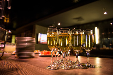 Glasses with champagne stand on a wooden table. Champagne in glasses on the blurred background of the bar. A glass with alcohol.