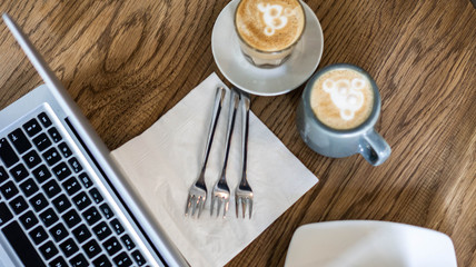 Coffee on the table near laptop and forks