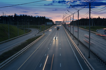 Fototapeta na wymiar fast cars on highway in evening light. Road with metal safety barrier or rail. Sunset