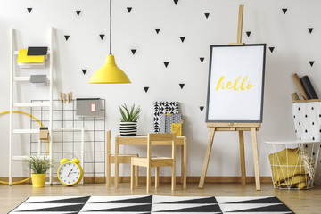 Playroom and study corner for a child in a fun room interior with wooden furniture, yellow lamp and...
