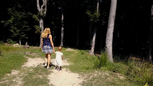 Mother and little girl walking in the forest. Woods trail. Parenting and family time concept