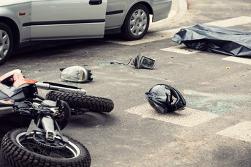 Black helmet and motorcycle on the road after fatal collision with a car