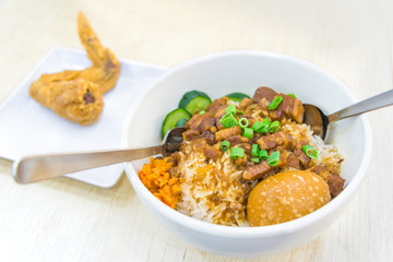 Braised pork rice and egg and in sweet brown sauce with fried chicken wings delicious food in Singapore on wooden table