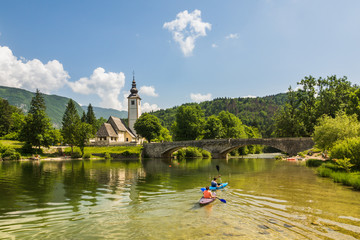 Naklejka premium Church and stone bridge over the Bohinj lake in Julian Alps, Triglav National Park, Slovenia