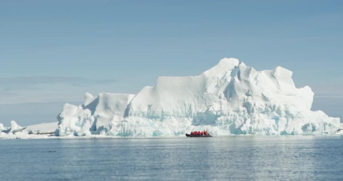 A zodiac manoeuvres below a giant iceberg in Antarctica.