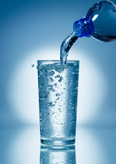 Obraz na płótnie Canvas Pouring soda water from bottle into glass