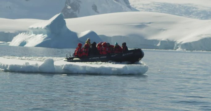 A boat load of people on board a zodiac (small boat) head out to explore icebergs whilst on a cruise in Antarctica.