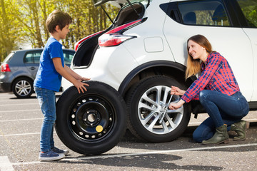 Fototapeta na wymiar Little boy helping his mother to change flat tyre