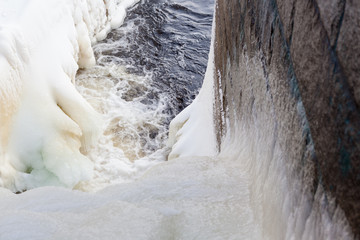 Dam at winter flowing water and ice formations