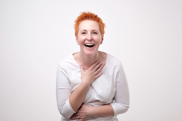 Fototapeta premium Close up portrait of a beautiful mid adult woman with red hair laughing standing on gray background.