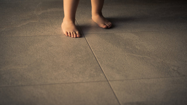 Barefoot baby are staying on heating tile floor.