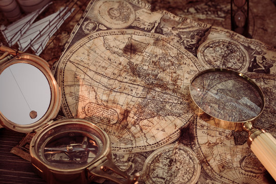 Old vintage maps and marine equipment like compass, magnifier or hourglass and ship. Columbus Day concept.